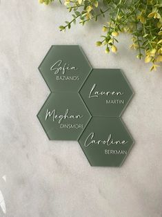 three hexagonal glass coasters with names on them sitting next to some flowers