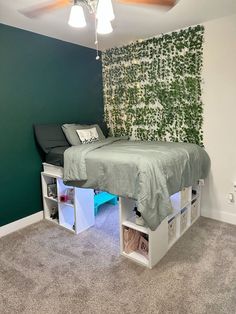 a bedroom with green walls and white shelving units underneath the bed is decorated with ivy leaves