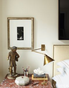 a small table with a lamp, book and other items on it in front of a framed photograph