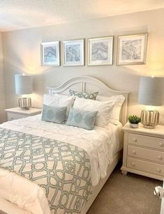 a white bed sitting in a bedroom next to two lamps and pictures on the wall