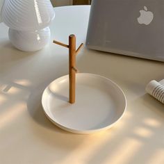 a white plate sitting on top of a table next to an apple laptop and cup