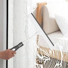 a person is using a window sealer to clean the glass in front of a bed