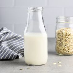 a glass bottle filled with oatmeal next to two jars full of oats