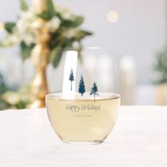 there is a wine glass that has two trees on the inside and happy holidays written on it