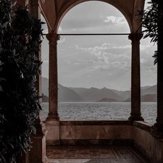 an archway with water and mountains in the background