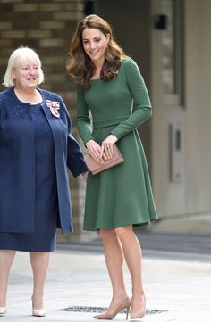 a woman in a green dress standing next to an older woman wearing a blue coat