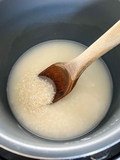 a wooden spoon stirring rice in a pot