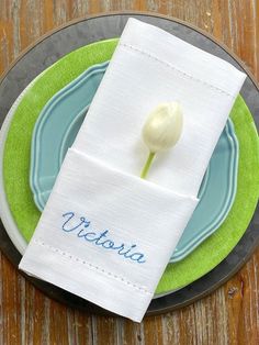 a white flower sitting on top of a blue and green plate next to a napkin