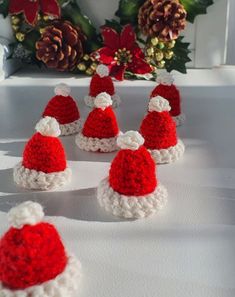 crocheted santa hats sitting on top of a table next to pineconis