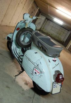 an old scooter is parked in a garage