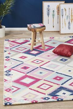 an area rug with colorful patterns and wooden stools in front of blue painted wall