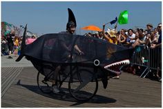 a man riding on the back of a bike with a shark head attached to it