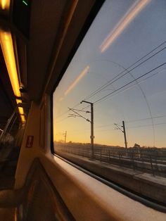 the sun is setting over an empty train track as seen from inside a vehicle window