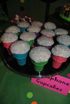 cupcakes with white frosting and sprinkles are on a black plate