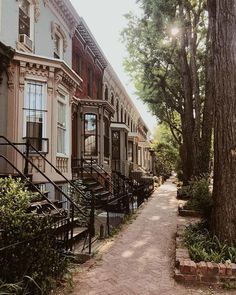 the sidewalk is lined with row houses and trees