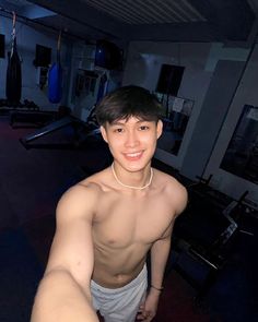 a shirtless young man is posing for the camera in a gym room with no shirt on