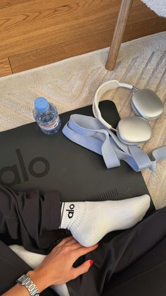 a person laying on a mat with headphones, water bottle and other items next to it