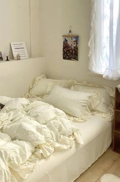 an unmade bed with white sheets and pillows