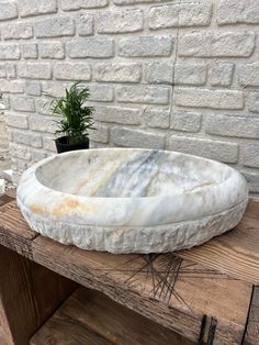 a white marble sink sitting on top of a wooden table