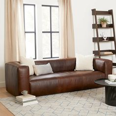 a brown leather couch sitting in front of a window