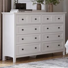 a white dresser with many drawers and vases on top