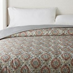 a bed with a white headboard and pillows on top of it, next to a window