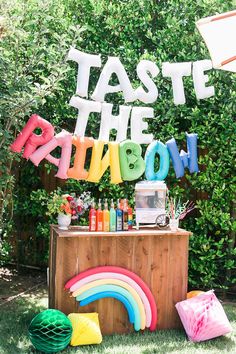 a party sign that says taste the rainbow on top of a table with balloons and decorations