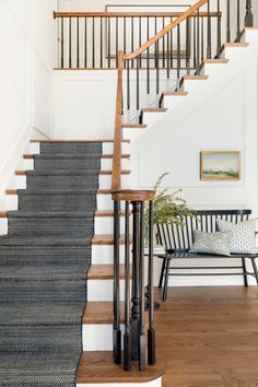 a staircase with black and white carpet next to a bench