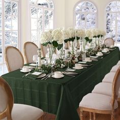 a long table is set with white flowers and place settings for an elegant dinner party