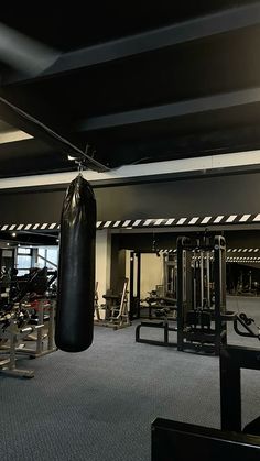 an empty gym with punching bags hanging from the ceiling and exercise equipment in the background