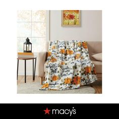 a living room with a couch, chair and table covered in a fall themed blanket