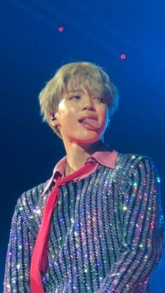 a person wearing a red tie and sequins on their shirt is standing in front of a blue background