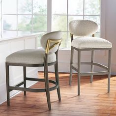 two chairs in front of a window with wood flooring and white walls behind them