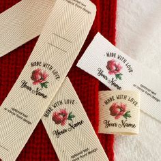 three labels on the side of a red and white towel with flowers printed on them