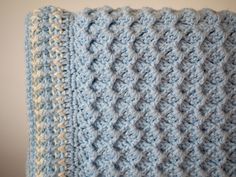 a blue and white crocheted blanket hanging on a wall