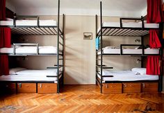 two bunk beds in a room with wooden floors and red drapes on the windows