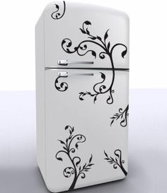 a white refrigerator with black floral designs on the front and bottom door, sitting on a gray surface