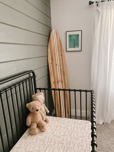 a teddy bear sitting on top of a bed next to a surfboard in a room