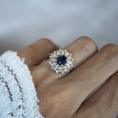 a woman's hand with a blue and white diamond ring on top of it