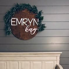 a white bed with a wooden sign hanging on the wall above it that says emryn bay