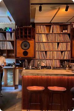 a man sitting at a table in front of a book shelf filled with record players