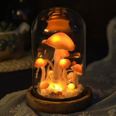 an illuminated mushroom in a glass dome on a doily