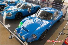 two blue sports cars are on display in a museum