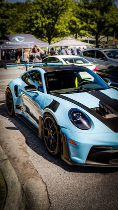 a blue and black sports car parked in a parking lot next to other cars on the street