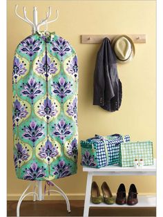 an ironing board and coat rack in front of a wall with shoes on it