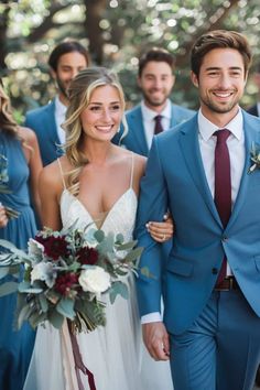 the bride and groom are walking with their bridal party in blue suits, burgundy ties