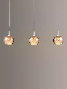 three light fixtures hanging from a ceiling in a room with gray walls and flooring