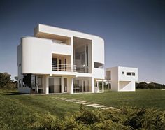 a large white building sitting in the middle of a grass covered field with stairs leading up to it