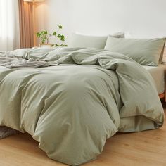 an unmade bed with green sheets and pillows