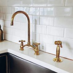 two brass faucets on a white kitchen counter